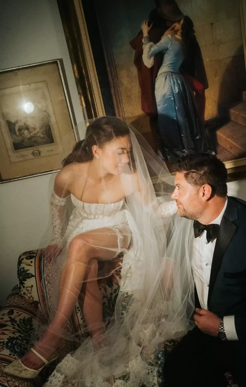 Intimate moment between bride and groom under a painting at Château Ste. Agnès, her veil softly draped around them.