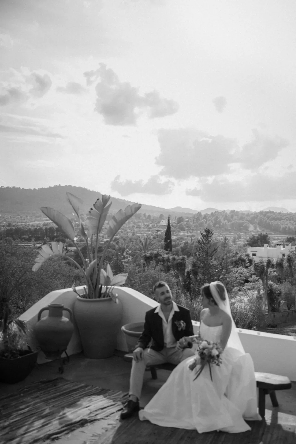 Bride and groom seated on a terrace with panoramic mountain views, intimate and cinematic black and white frame by Clarissa Sofía Studio.