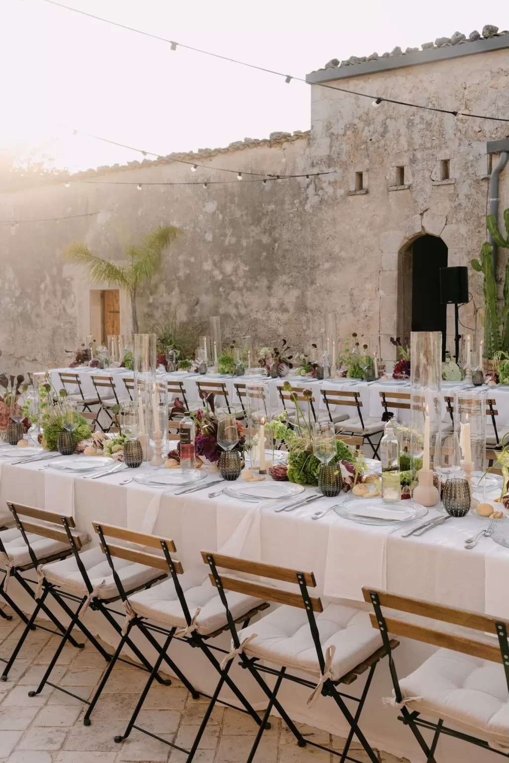 Elegant outdoor tablescape with soft linens, candles, and floral centerpieces at Dimora Delle Balze courtyard.