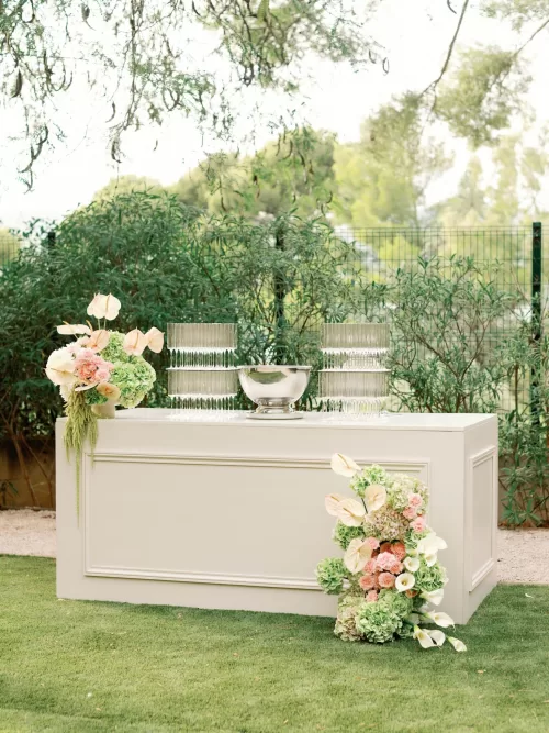 Elegant outdoor drinks station with floral arrangements set in the gardens of Domaine de Canaille