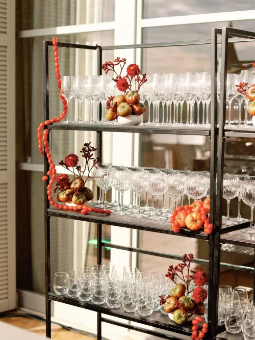Styled shelving with crystal glassware and bold red floral details at a Domaine de Canaille wedding reception
