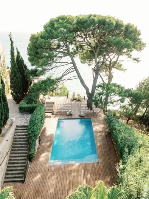 Ceremony setup overlooking the pool and sea beneath pine trees at Domaine de Canaille