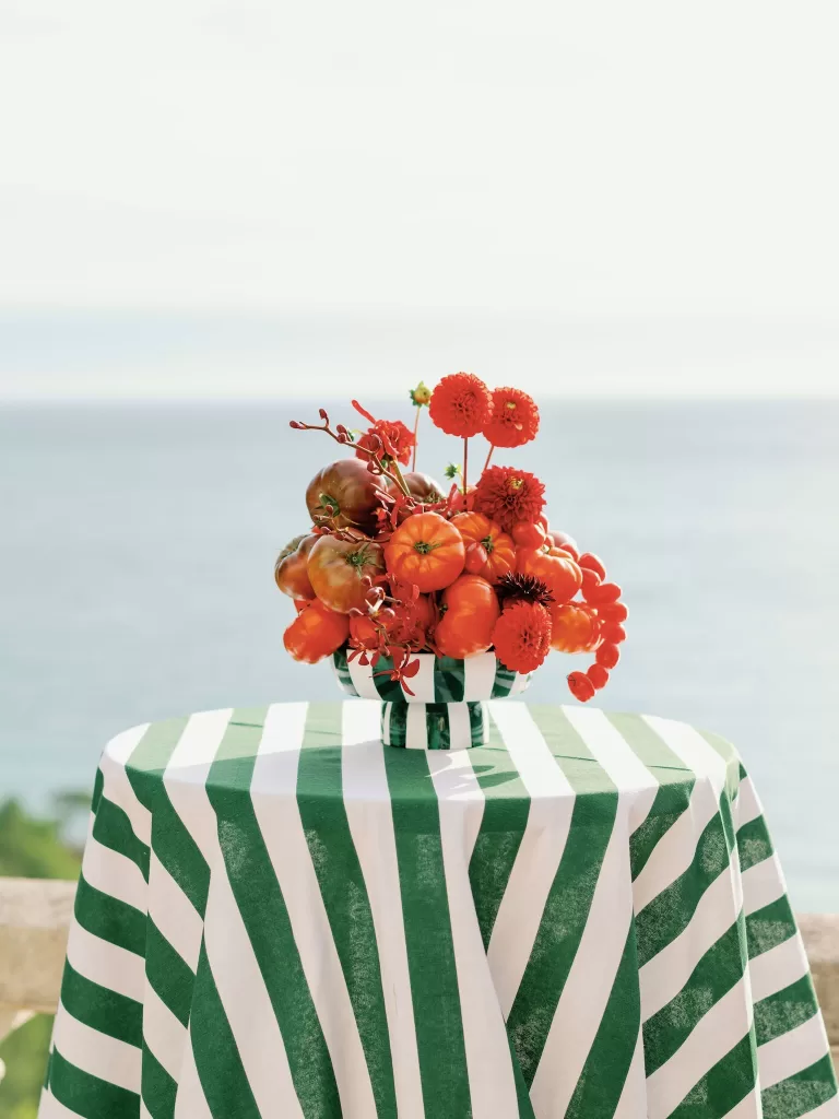 Cocktail table dressed in green striped linens with tomato and floral arrangement overlooking the sea at Domaine de Canaille