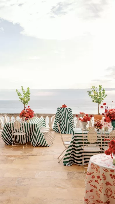 Reception tables dressed in green striped linens with sea views on the terrace at Domaine de Canaille