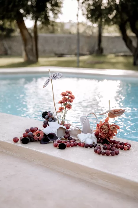 Bridal shoes styled poolside at Finca Morneta with grapes and florals, reflecting the relaxed Mediterranean setting.