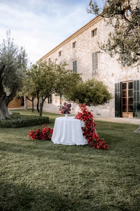 Wide garden view at Finca Morneta with a floral-adorned wedding cake table set against the rustic stone walls.
