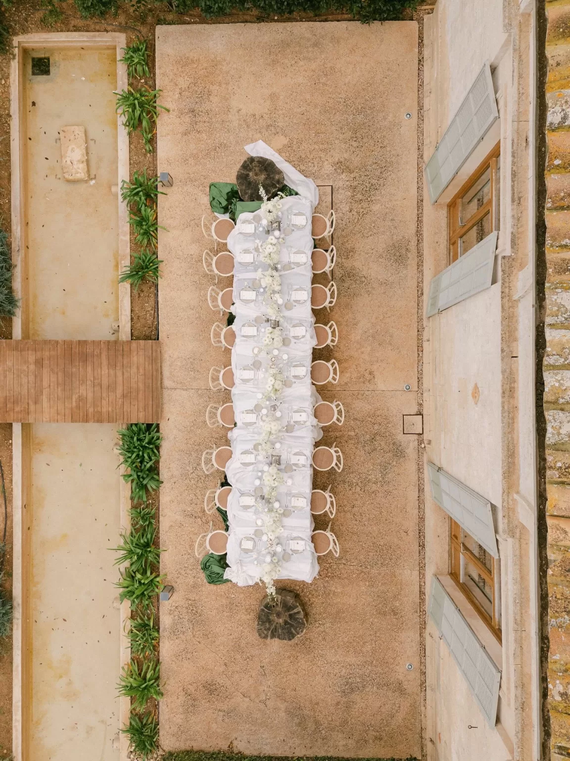 Overhead view of a long wedding table at Fontsanta with white florals, candles and symmetrical courtyard layout.