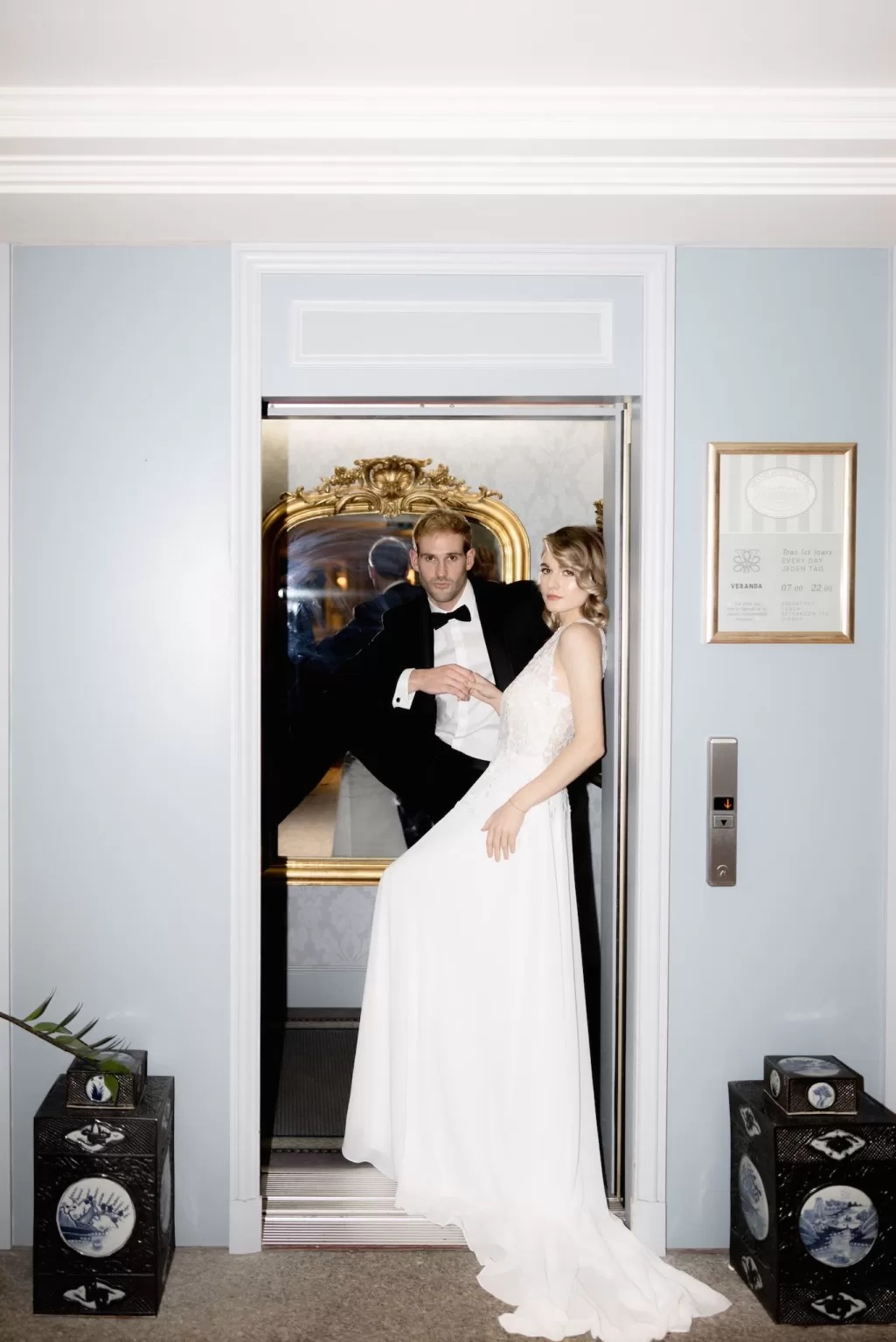 Bride and groom posing inside a vintage elevator at Grand Hotel du Lac, blending modern fashion with classic hotel charm.