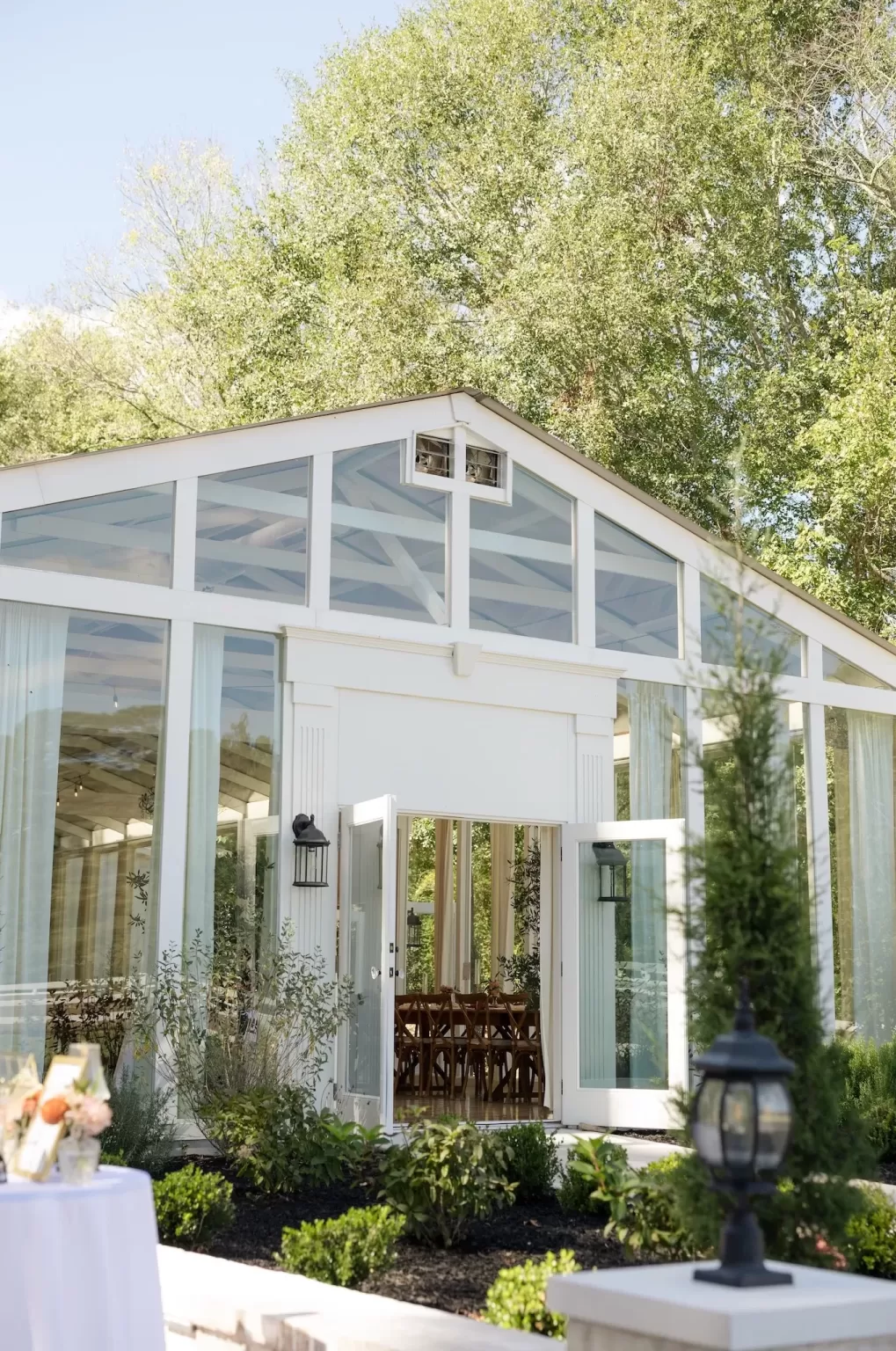 Sunlight reflects off the glass walls of The Greenhouse at Arrows Farm, highlighting its modern white exterior.
