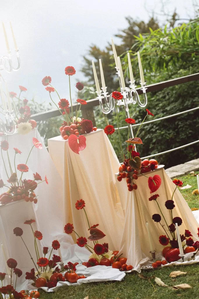 Layered ceremony styling with red flowers, tomatoes and glass candelabras on terrace at Hotel Ristorante La Darsena.
