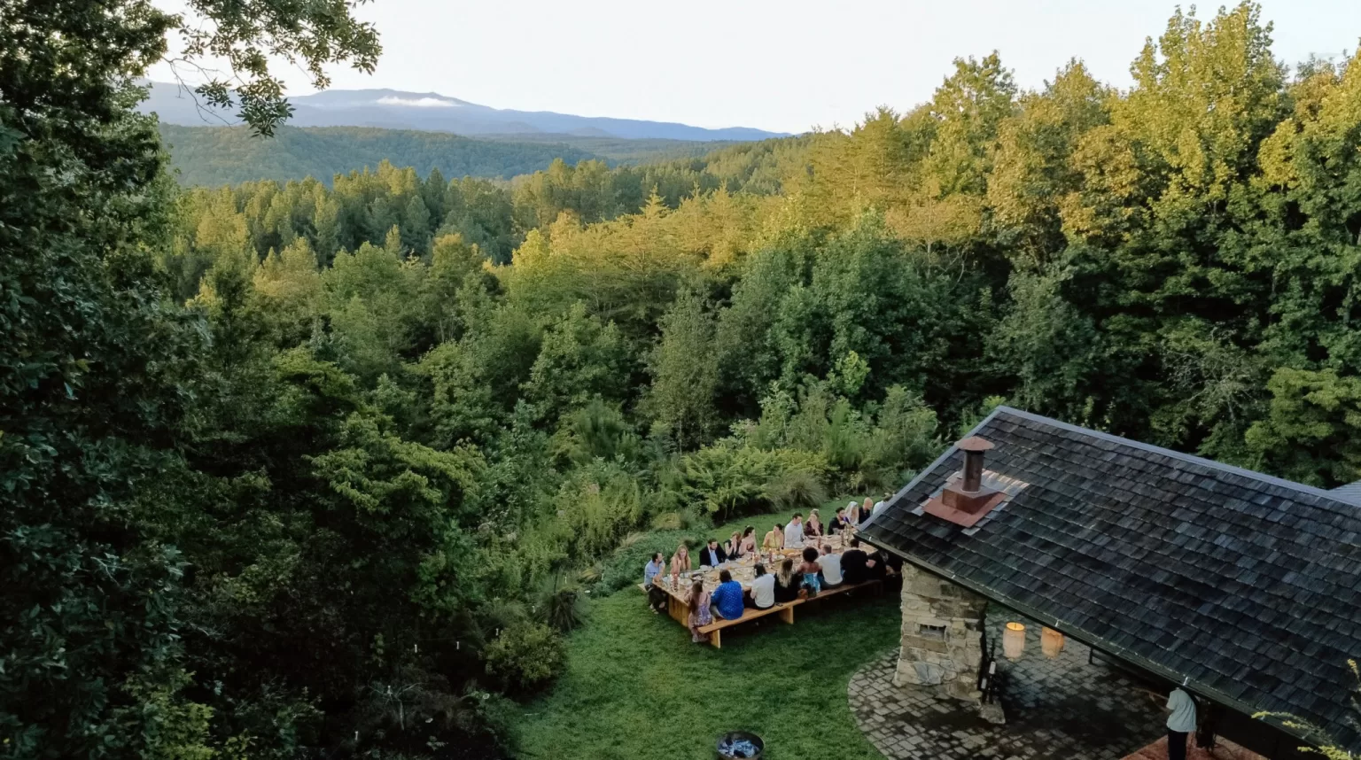 Long outdoor dinner table at House Boheme overlooking rolling mountain views, capturing an intimate al fresco wedding reception.