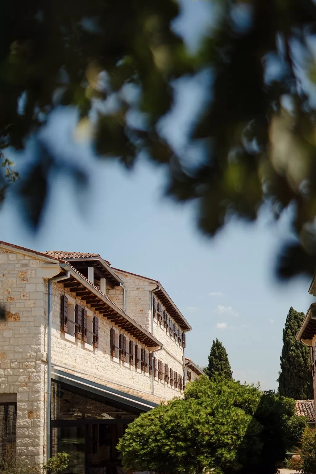 Detail of rustic stone architecture at Meneghetti Wine Hotel, surrounded by lush greenery.