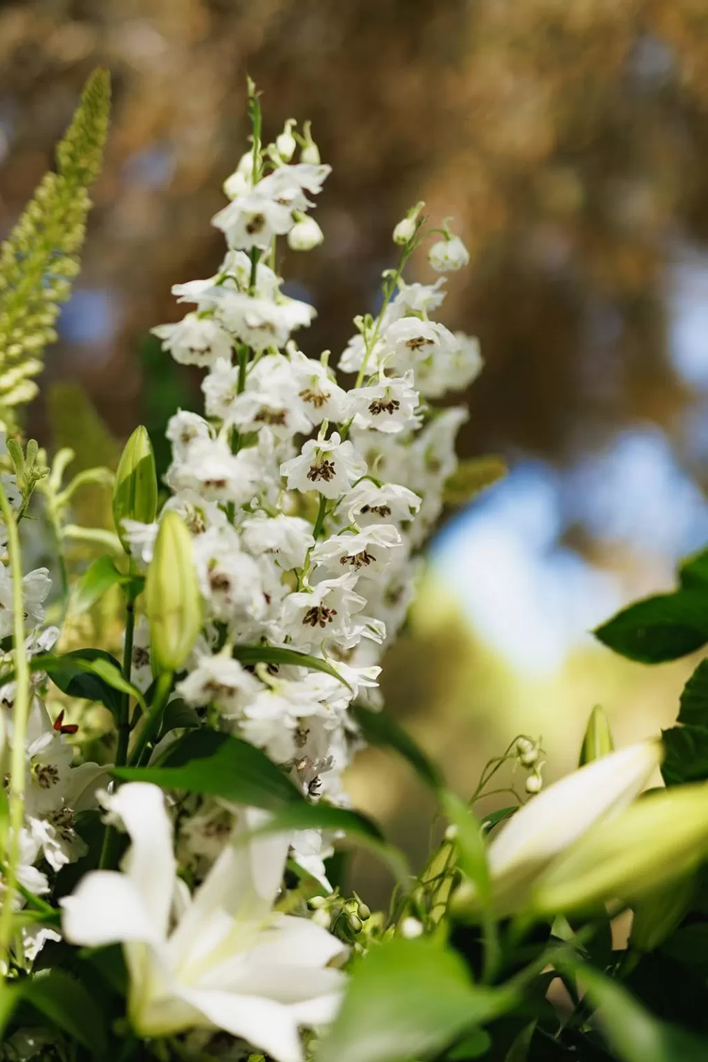 Detail of white delphinium flowers and lilies from a Meneghetti Wine Hotel wedding ceremony arrangement.