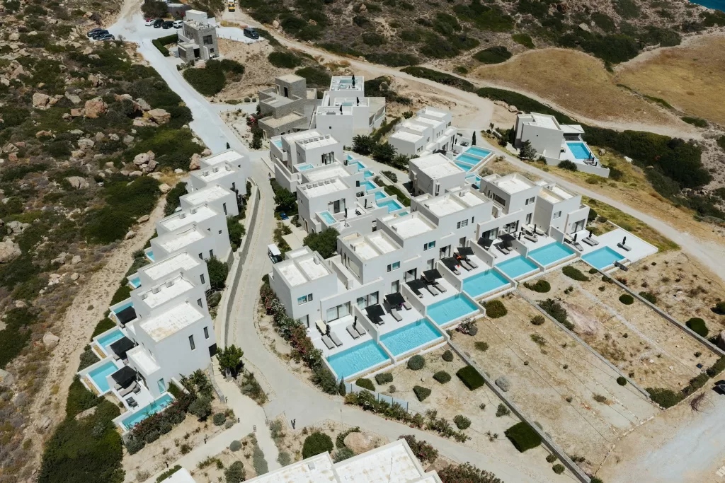 Aerial view of Milos Cove villas with private infinity pools set into the rugged hillside.