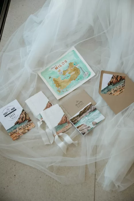 Milos-inspired wedding stationery and invitations styled on soft bridal veil fabric at Milos Cove.