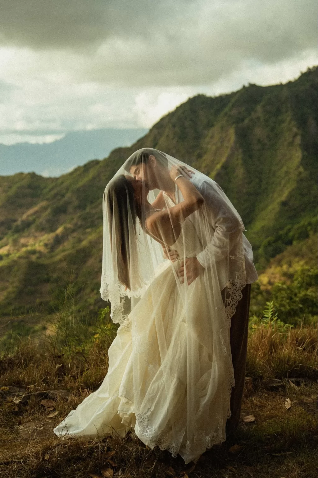 Romantic veiled kiss between bride and groom overlooking the landscape at Ossipoff’s Cabin, captured in gentle natural light.