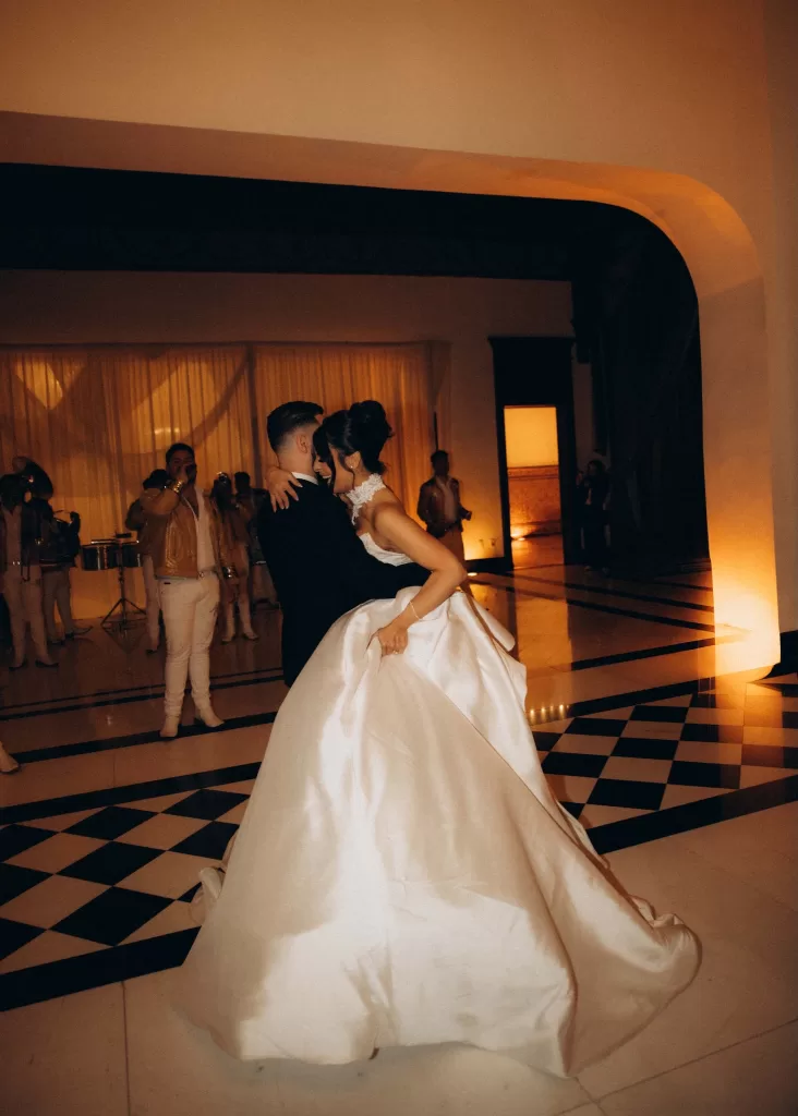 Bride and groom sharing their first dance at Palacio Metropolitano on a black and white tiled floor surrounded by live musicians.