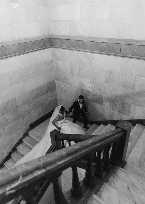 Bride and groom walking down the marble staircase at Palacio Metropolitano in a timeless black and white portrait.