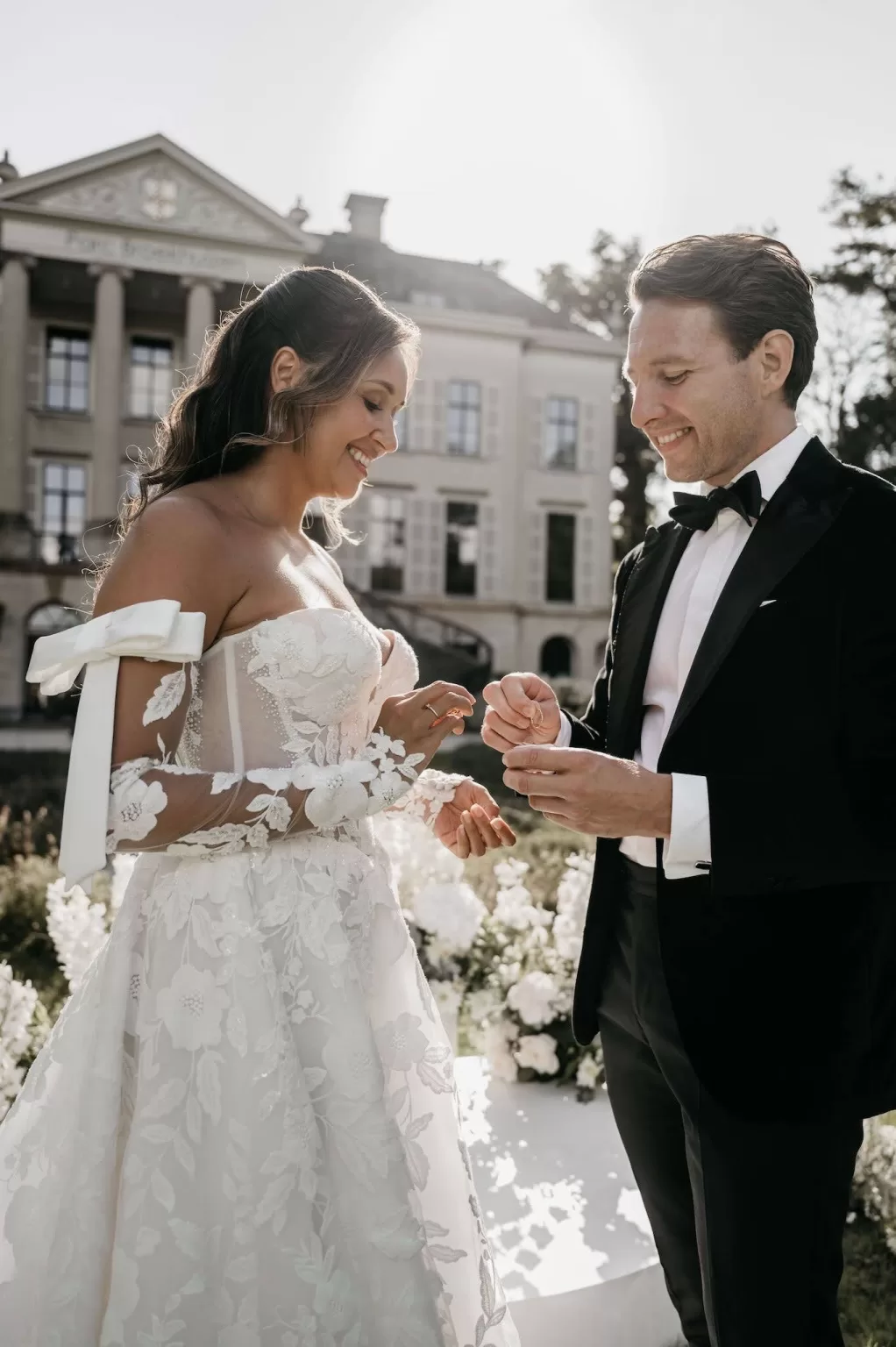 Bride and groom exchanging wedding rings in front of Parc Broekhuizen.
