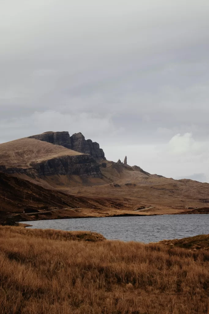 Breathtaking view of the Old Man of Storr with surrounding grassy hills and loch in Scotland.