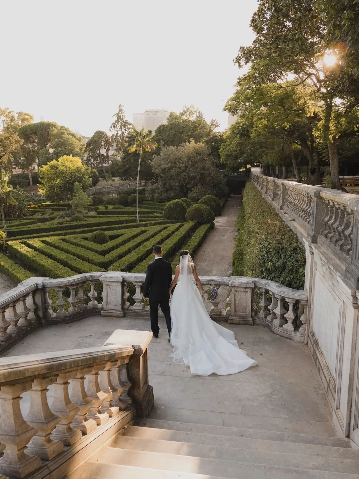 Newlyweds pausing at the balustrade with sweeping views over the formal gardens at Vandelli Botanical Garden.