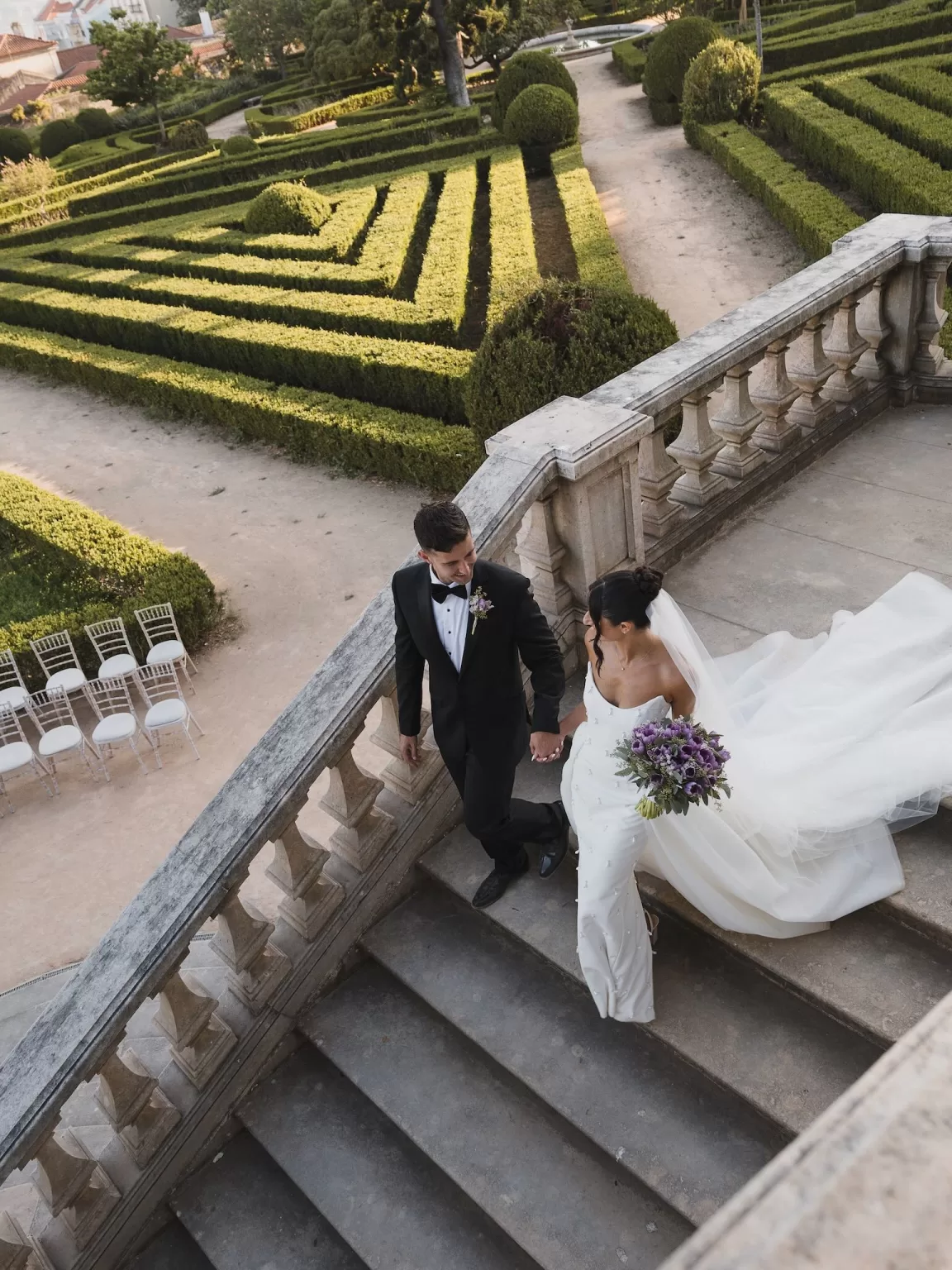 Bride and groom walking down the staircase with sweeping views over the formal gardens at Vandelli Botanical Garden.