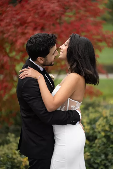 Bride and groom smiling at each other beneath vibrant autumn trees at Villa Honegg.