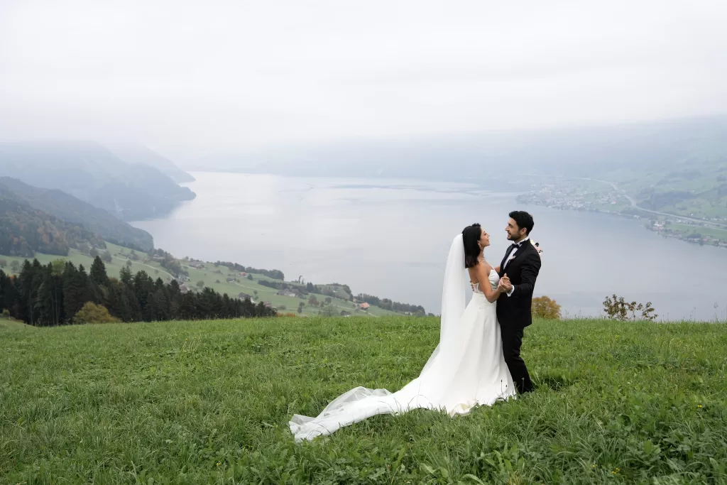 Bride and groom standing in alpine meadow with sweeping Lake Lucerne views near Villa Honegg.