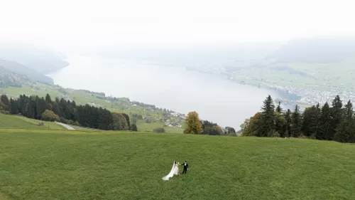Couple standing in alpine meadow overlooking Lake Lucerne after their Villa Honegg wedding ceremony.