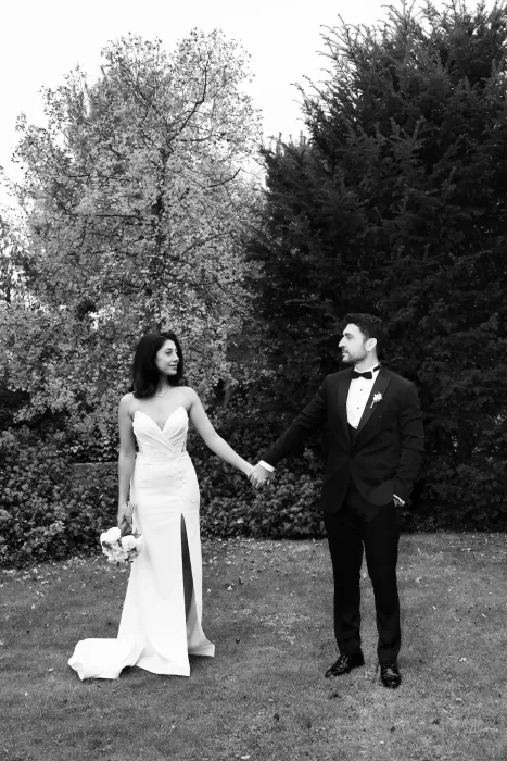 Bride and groom holding hands in the manicured gardens of Villa Honegg in Switzerland.