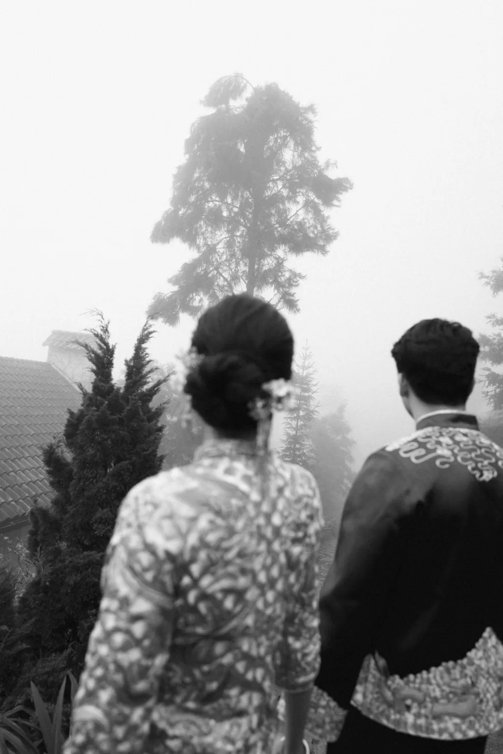 Bride and groom in traditional attire standing together in a misty forest setting near Ville de Mont Mountain Resort.