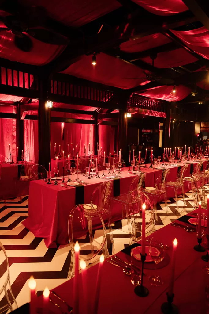 Red draped ceiling and candlelit dining tables at Ville De Mont Mountain Resort creating a moody, immersive reception setting.