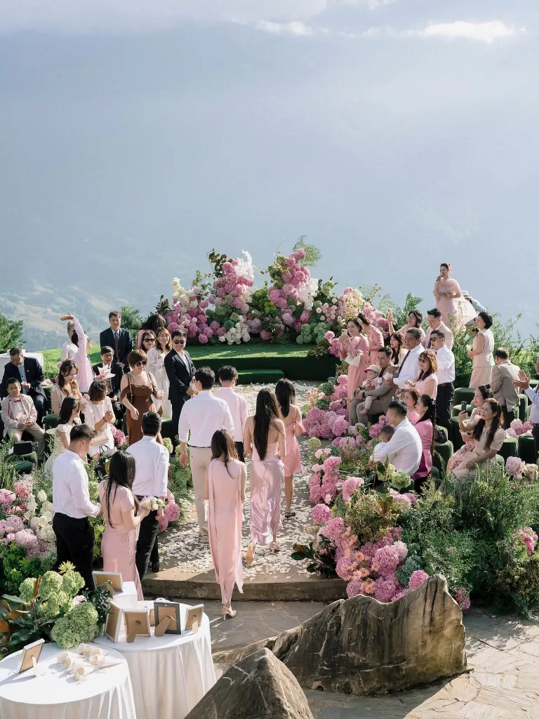 Wedding guests arriving at an outdoor ceremony space at Ville De Mont Mountain Resort surrounded by pink florals and mountain views.