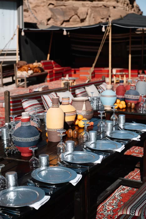 Close view of reception table styling at Wadi Rum with silver plates, patterned textiles and ceramic vessels.