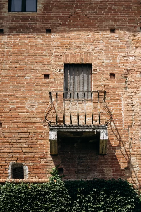 Rustic brick facade with small balcony and iron railing at Castello di San Fabiano