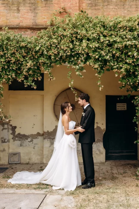 Couple standing together beneath ivy-covered archway at Castello di San Fabiano, soft romantic portrait