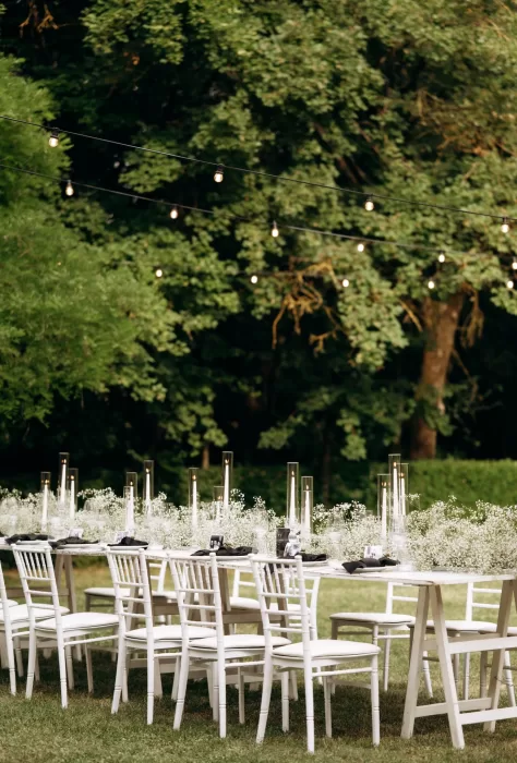 Outdoor reception tables with candles and greenery set beneath trees at Castello di San Fabiano