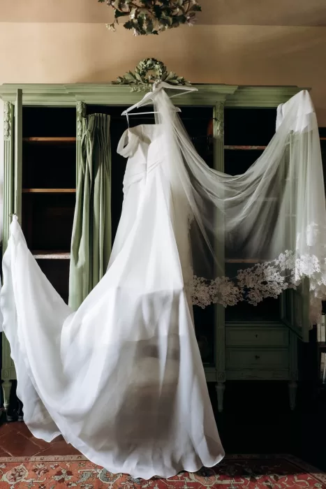 Wedding dress and veil hanging in vintage wardrobe at Castello di San Fabiano
