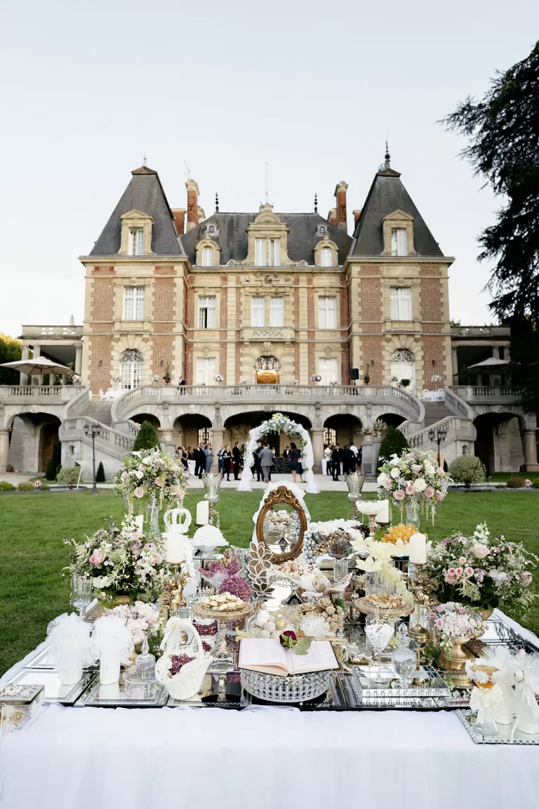 Outdoor wedding ceremony setup with floral arch and ornate reception table in front of Château Bouffémont’s grand façade.