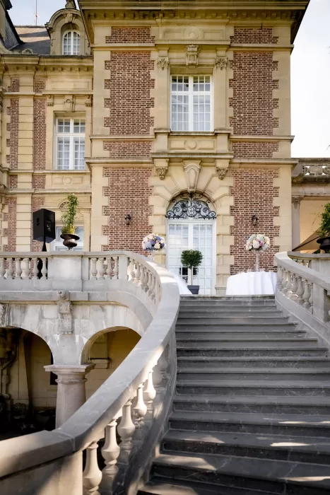 The grand curved staircase and historic brick façade of Château Bouffémont prepared for a wedding reception.