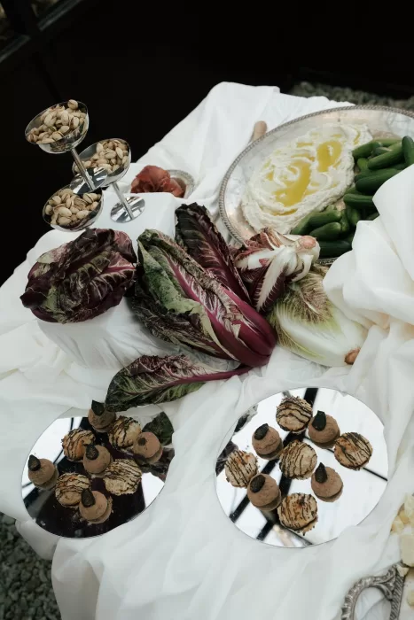 Styled cocktail hour food display with vegetables, pistachios, and desserts arranged on draped white linens at Common Goods.