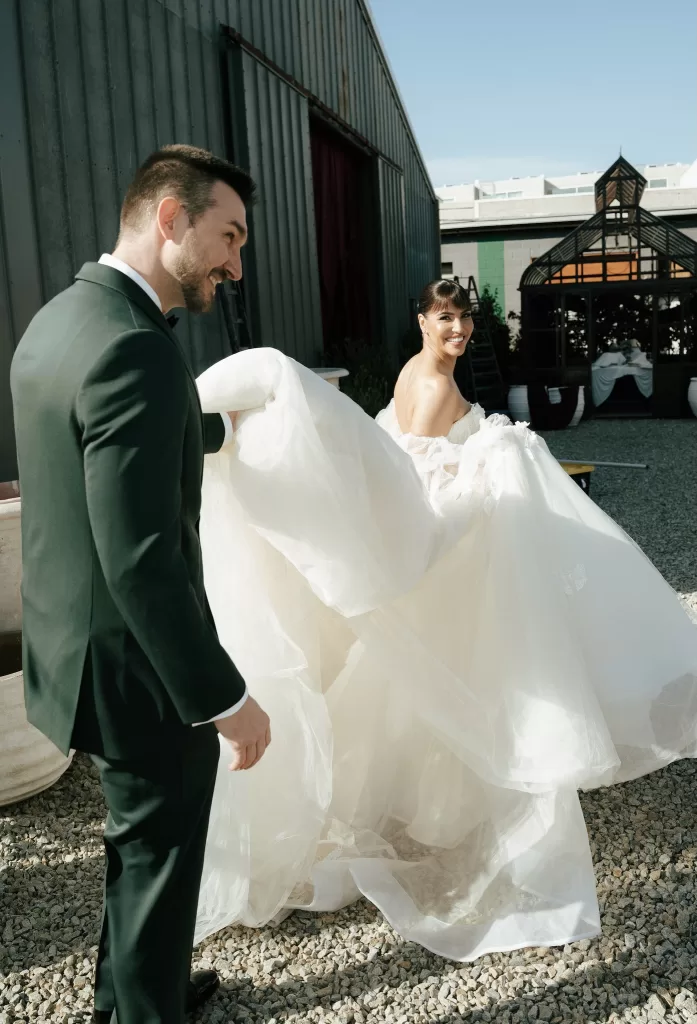 Bride and groom walking together across the gravel courtyard outside Common Goods wedding venue.