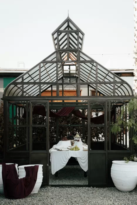 Glass greenhouse reception space at Common Goods set with a draped table and styled wedding décor.