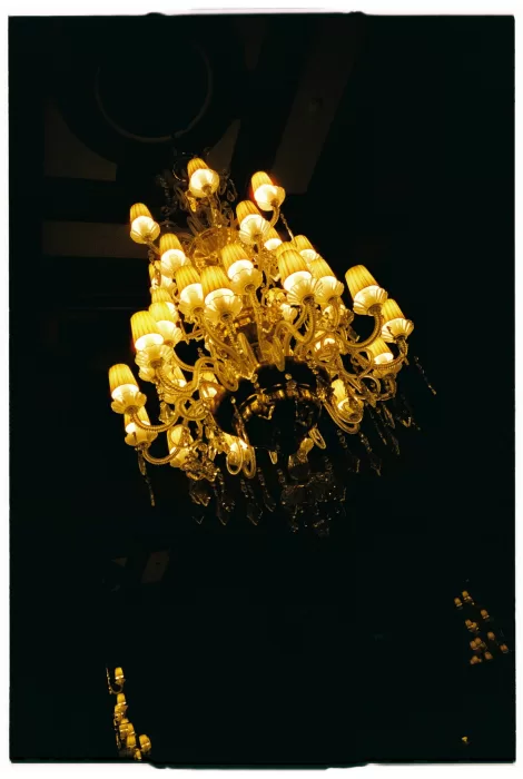 Ornate chandelier glowing warmly in the historic ballroom at Infante Sagres.
