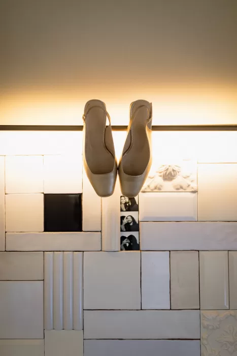 Bride’s ivory wedding shoes hanging against tiled wall with small photo booth strip at Infante Sagres.