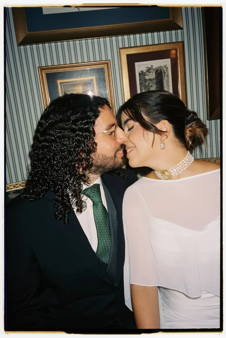 Close portrait of the bride and groom sharing a kiss against framed artwork inside Infante Sagres hotel.