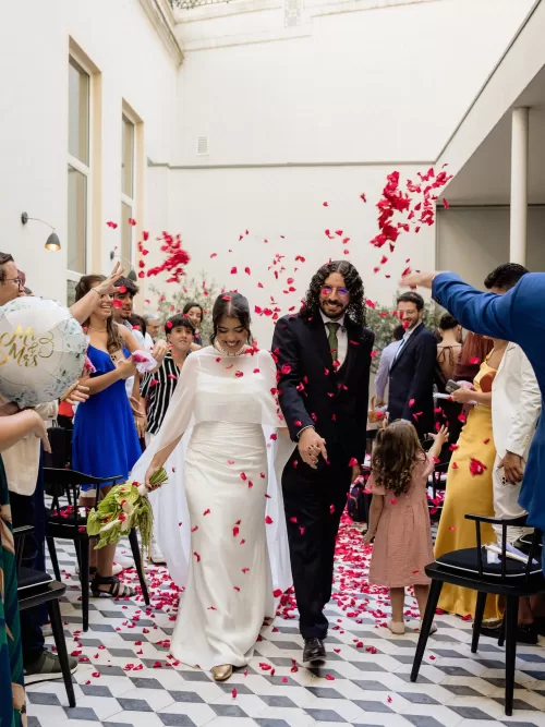 Newlyweds walking through guests throwing red rose petals in the courtyard at Infante Sagres.