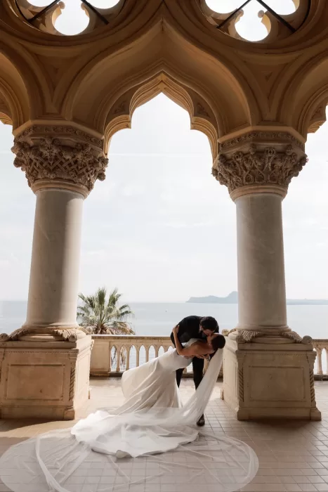 Couple sharing dip kiss beneath grand archway overlooking Lake Garda at Isola del Garda