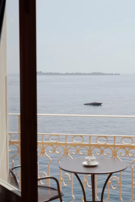 Minimal balcony scene with coffee table overlooking calm Lake Garda waters at Isola del Garda