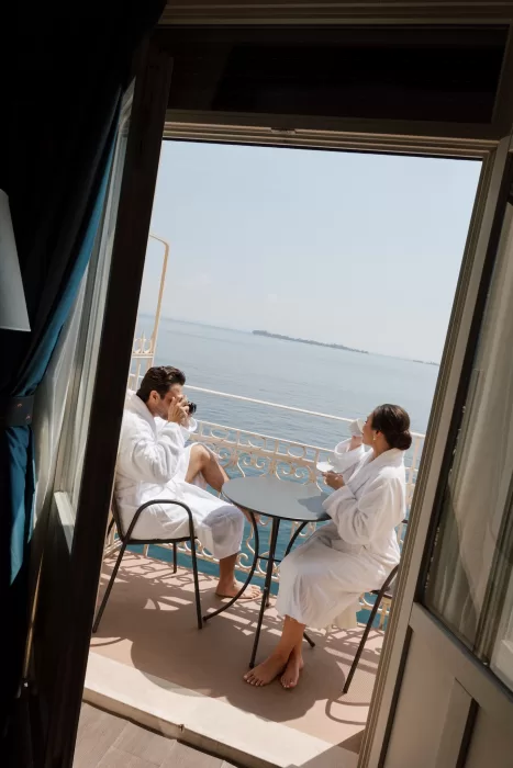 Couple in robes enjoying coffee on balcony overlooking Lake Garda at Isola del Garda